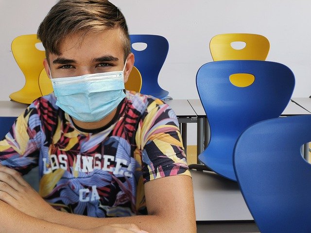 mask-wearing student sitting in classroom